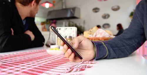 Man Holding Smartphone at Modern Cafe Table