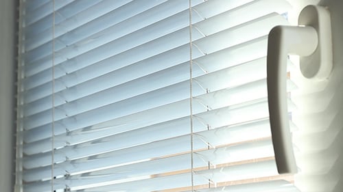 White Blinds Lowering Over Open Window