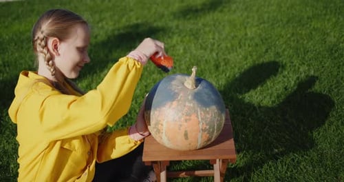 A Girl of 10 Years Old Paints Pumpkins Prepares Jewelry for Helloween