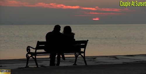 Couple Sitting on Bench Watching Ocean Sunset