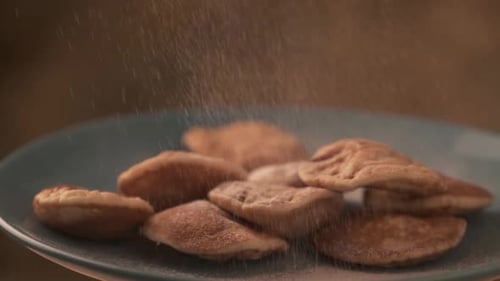 Powdered Sugar Falling onto Mini Pancakes on Plate
