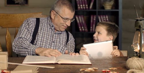 Adult and Child Reading and Using Tablet Indoors