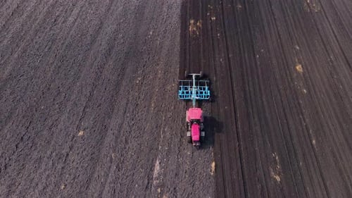 Tractor Plows Ground on Cultivated Farm Field