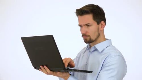 A Young Handsome Man Works on a Notebook, Then Smiles at the Camera - White Screen Studio