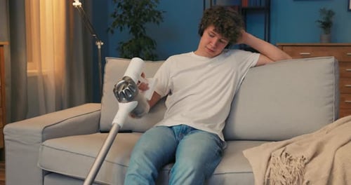 Un jeune garçon passe l'aspirateur compulsivement dans la chambre le soir alors qu'il est assis sur le canapé