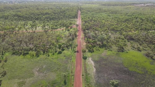 High Slow Moving Aerial Drone shot of Long Straight Red Road and Green Bushland Near Holmes Jungle N