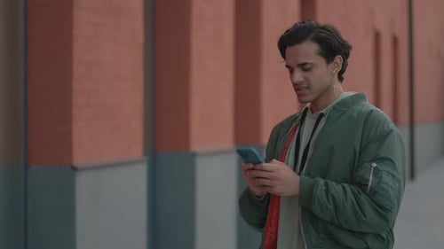 Young Man Smiling Using Smartphone in the City