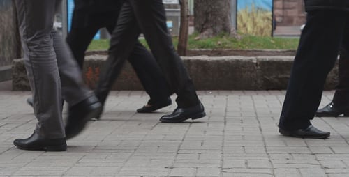 Feet of People Walking on Sidewalk in City