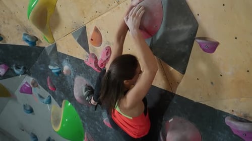 Woman Climbs Rock Wall in Indoor Climbing Gym