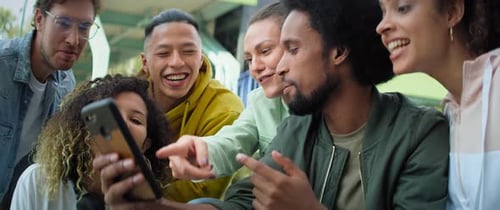 Friends Laughing Together While Looking at a Phone