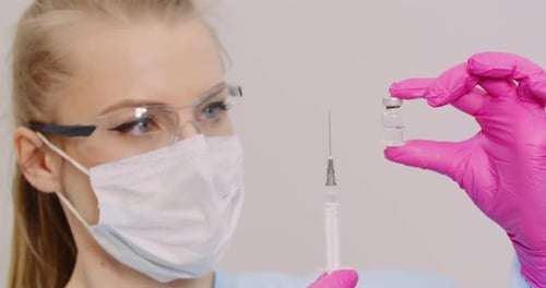 Arzt hält Spritze und Impfstoff in der Hand