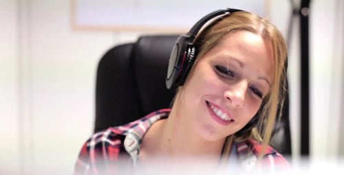 Smiling Woman Wearing Headphones Working at Computer
