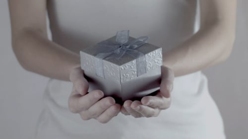 Woman Hands a Gift Forward in Close Up