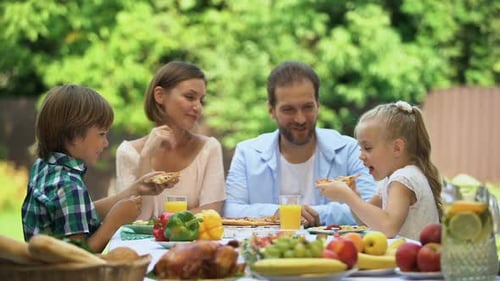Happy Family Eating Pizza Together Outdoors