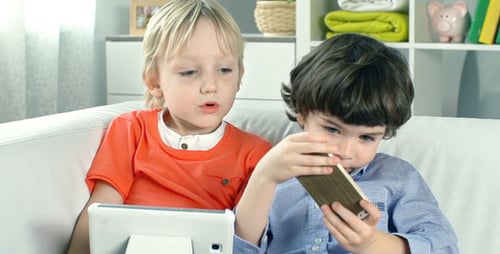 Two Young Boys Play on Phone and Tablet