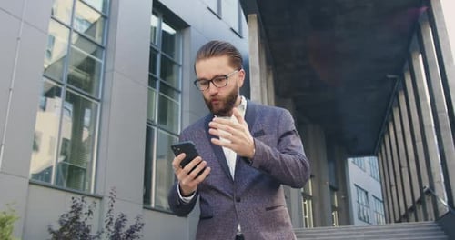 Businessman Seeing Good News on Phone Screen while Standing Near Office Center