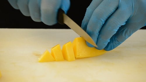 Hands in Gloves Slice Mango on Cutting Board