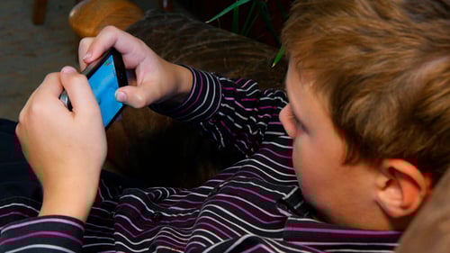 Boy Playing Mobile Game on Phone Indoors