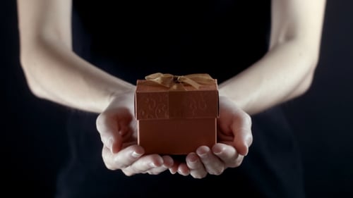 Hands Presenting Small Gift with Gold Ribbon