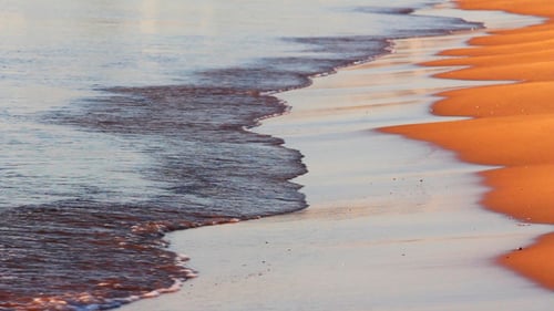 Meereswellen und Sandstrand im Morgengrauen