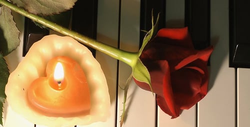 Red Rose and Candle on Piano Keyboard
