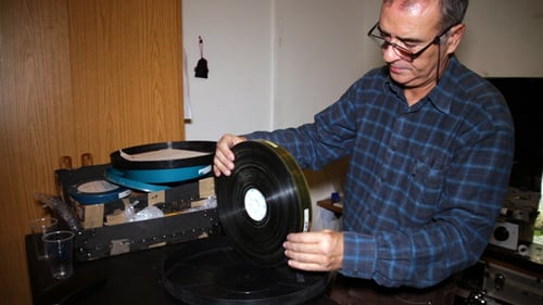Man Placing Film Reel on Film Editing Machine