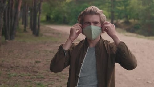 Portrait Of Man Taking Off Face Mask In Forest
