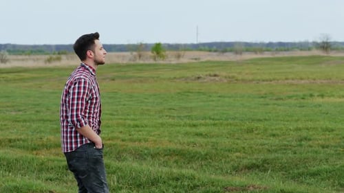 Happy Hipster Guy Walks in the Field at Sunset, Smiles, Feels Free