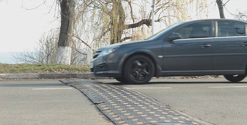 Cars and Vans Driving Over a Speed Bump
