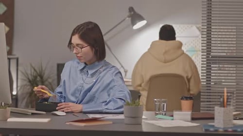 Woman Eating and Working at Night Office