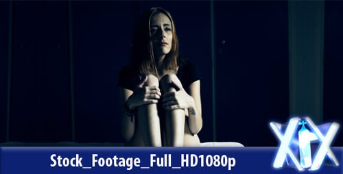 Sad Young Woman Sitting On Bed At Night