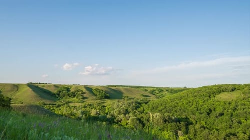 Zeitraffer. Wolken im blauen Himmel über dem Horizont. Malerische grüne Hügel