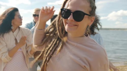 Fröhliche Studentin hat Spaß mit Freunden beim Tanzen auf einer Party im Freien am Strand