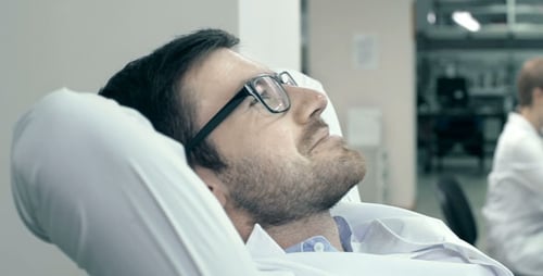 Young Scientist Leans Back in Chair in Lab