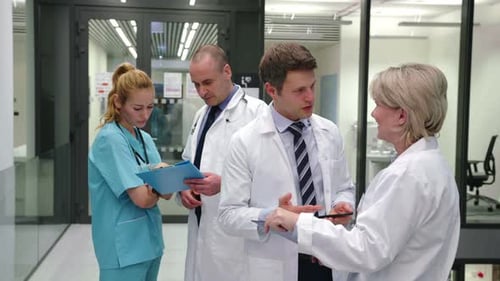 Medical Team Discussing Patient Charts in Hospital Hallway