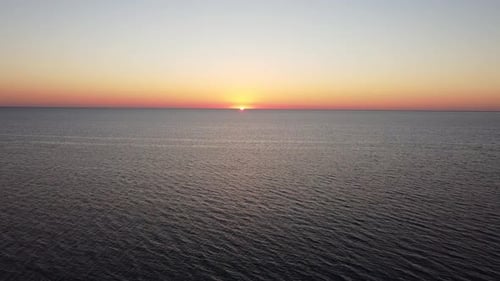Bird's Eye View of the Calm Water Surface of the Sea During the Orange Evening Sunset on the Horizon