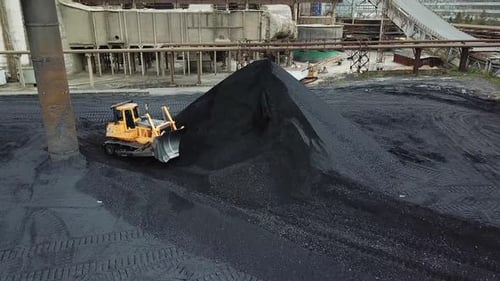 Bulldozer Pushing Pile of Material in Industrial Area