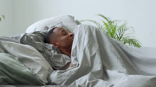 Man Waking Up and Stretching in Bedroom