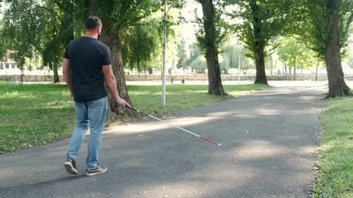 Junger blinder Mann geht im Park spazieren
