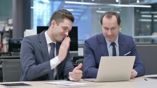 Two Businessmen Collaborating on Laptop in Modern Office