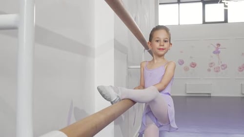 Beautiful Little Ballerina Girl Stretching on Ballet Bar at Dance School