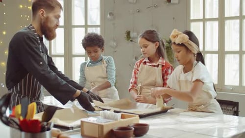 Kinder und Koch legen während des Kochkurses Teig auf Backbleche