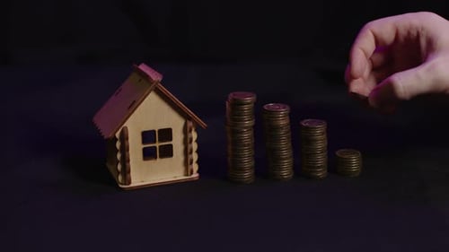 Small Wooden House with Columns of Coins on Black Background