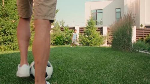Father and Child Play Soccer on Lawn
