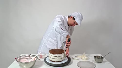 Woman Decorating Multi-Layered Cake with White Frosting