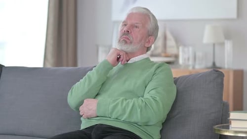 Ernsthafter alter Mann sitzt zu Hause und denkt nach