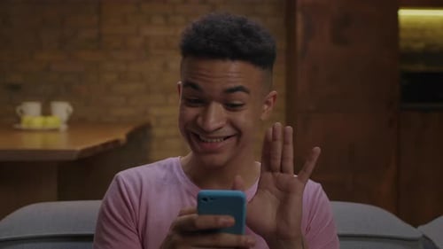 Man Smiles at Smartphone, Video Chat Indoors