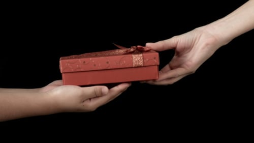 Hand Gives Red Gift Box to Another Hand