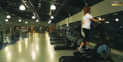Young Woman Uses Elliptical Cross in a Gym