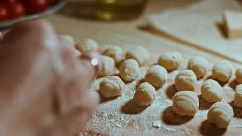 Chefkoch schneidet Kartoffelteigrollen für die Zubereitung von hausgemachten Gnocchi Angenehme Atmosphäre